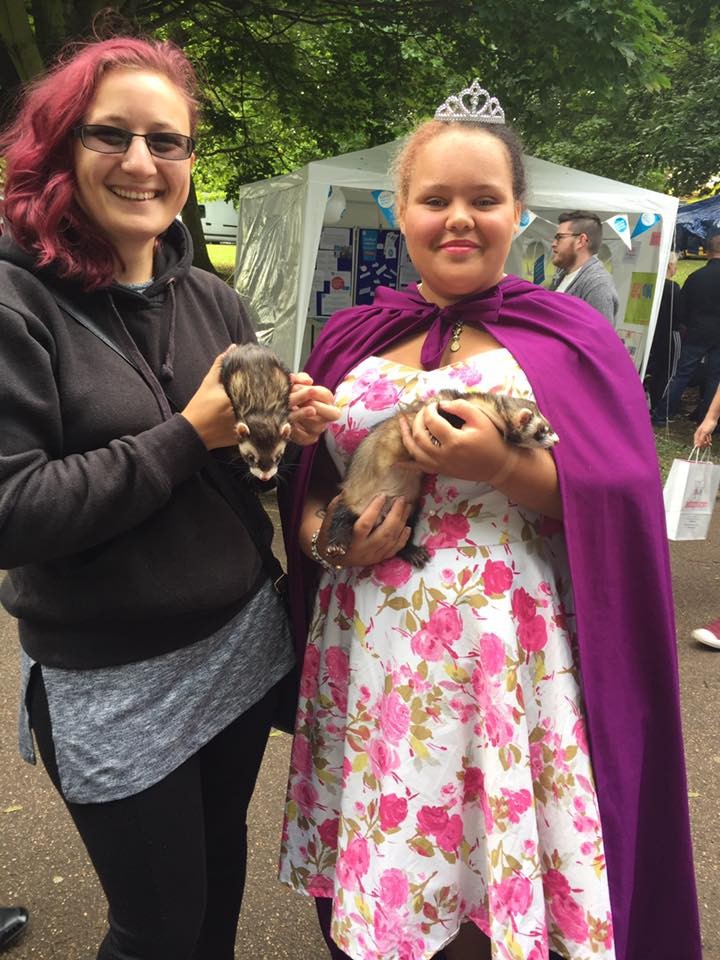 Two young ladies one dressed as a princess holding ferrets